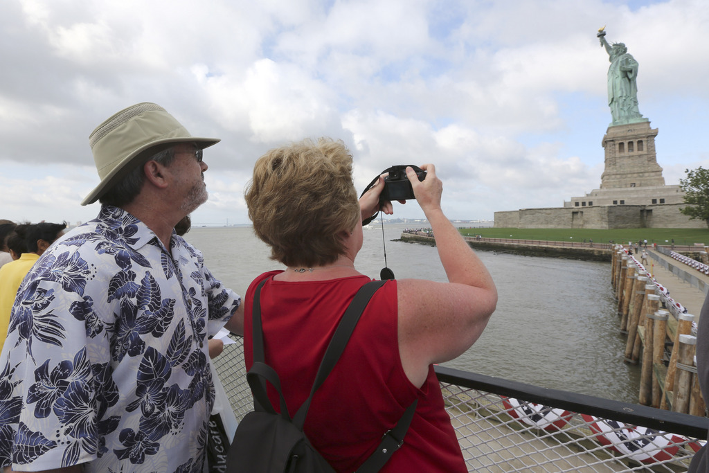 Rodney and Judy Long, of Charlotte, N.C., take a photo of the Statue of Liberty as they arrive on the first tourist ferry to leave Manhattan, Thursday, July 4, 2013 at  in New York. The Statue of Liberty finally reopened on the Fourth of July months after Superstorm Sandy swamped its island in New York Harbor as Americans across the country marked the holiday with fireworks and barbecues. (AP Photo/Mary Altaffer)