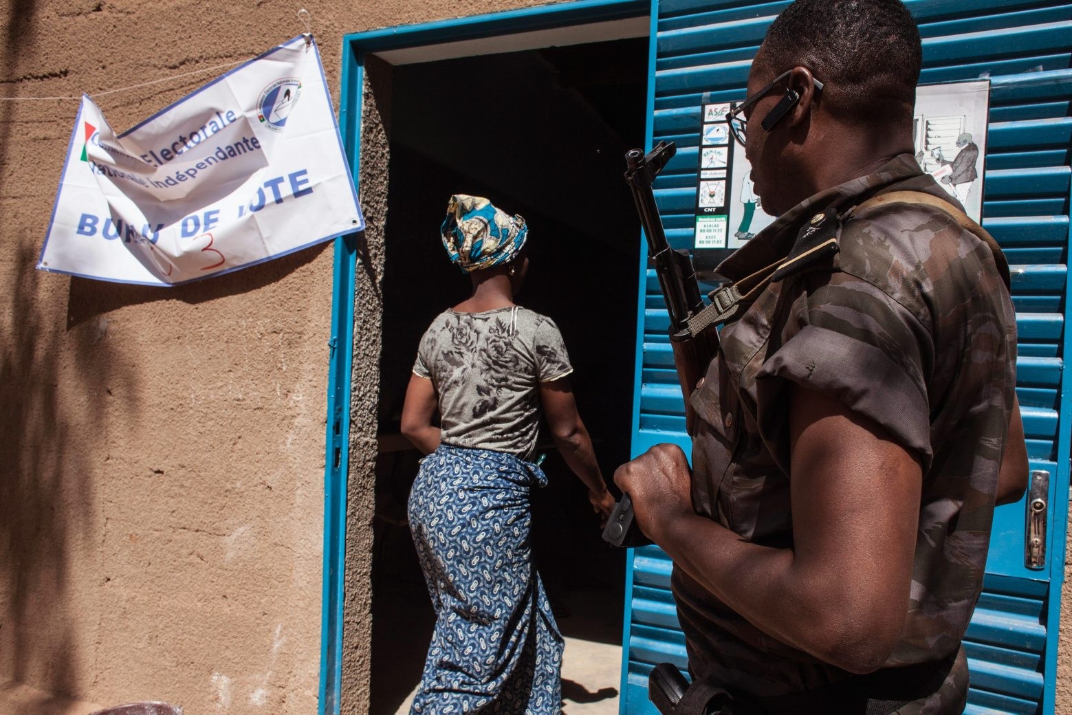 A Burkina Faso troop, right, provides security outside a polling station, as a woman voter enters the station to cast her ballot during elections in Ouagadougou, Burkina Faso, Sunday, Nov. 29, 2015. Hundreds of voters lined up after morning prayers to vote Sunday in Burkina Faso's first presidential and legislative elections since a popular uprising toppled the West Africa nation's longtime leader last year.(AP Photo/Theo Renaut) Burkina Faso Election