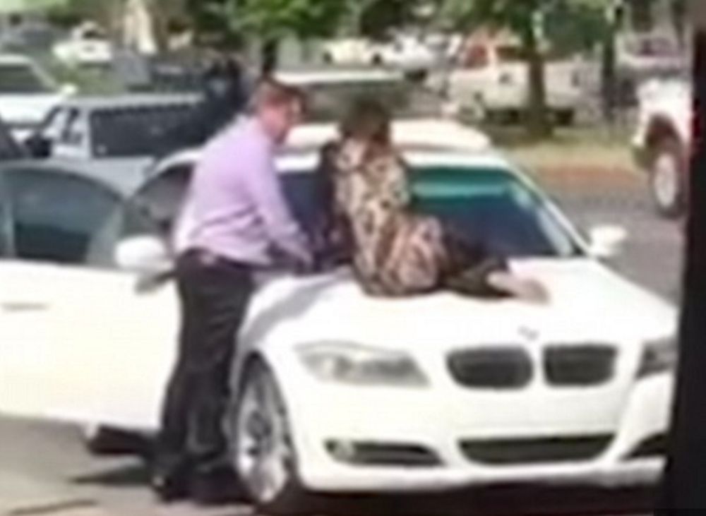 La femme refuse de libérer le capot de la voiture de son mari.