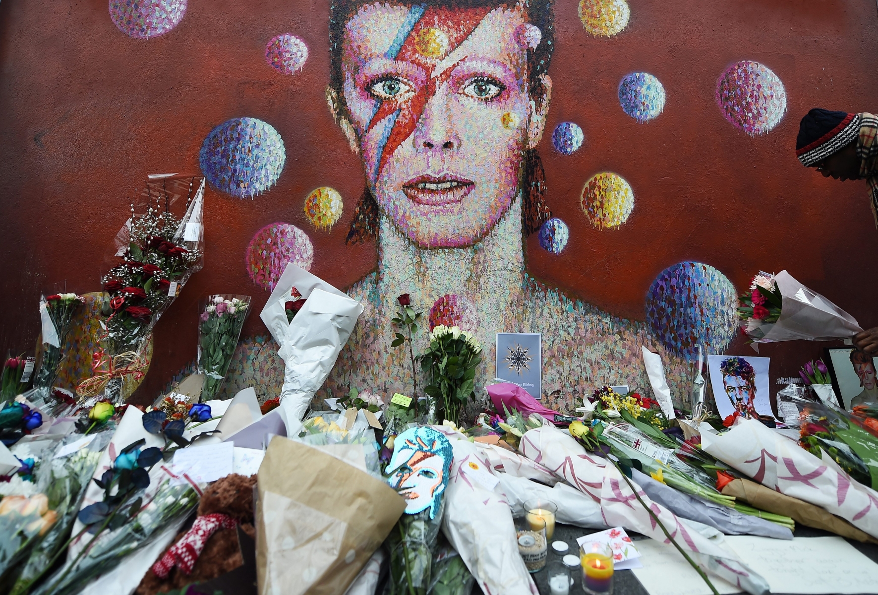epa05097191 Flowers at a tribute mural for British singer David Bowie in Brixton, birth place of the late David Bowie in London, Britain, 11 January 2016.  Well-wishers have flocked to the Bowie mural to pay their respects following the announcement of his death.  EPA/ANDY RAIN