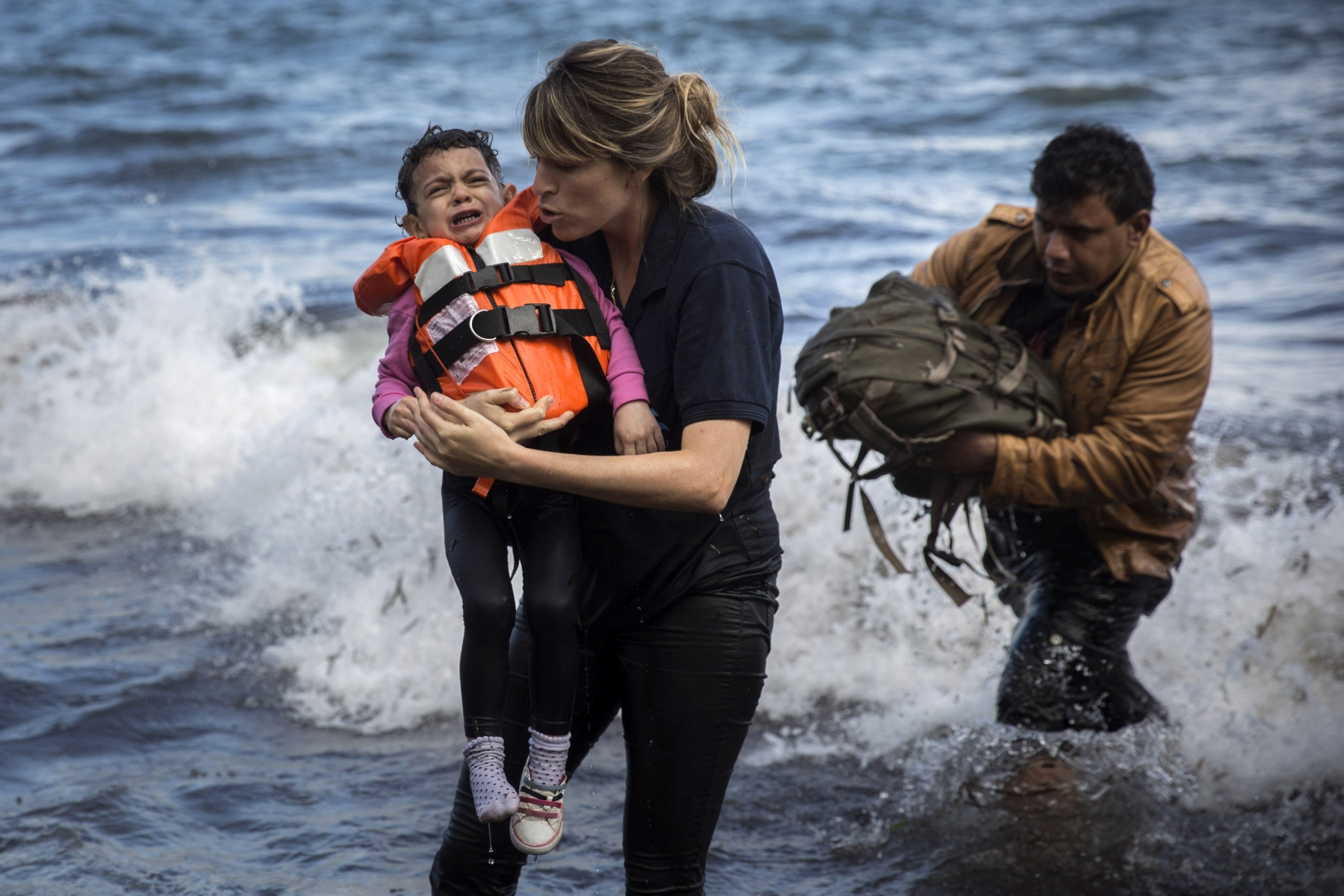 Une volontaire sort un enfant syrien de l’eau alors que sa famille arrive sur l’île grecque de Lesbos, fin septembre 2015.