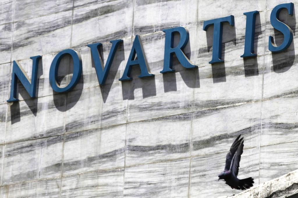 FILE - In this April 1, 2013 file photo, a dove flies near the logo of Novartis India Limited at their head office in Mumbai, India. A new study released Saturday, Aug. 30, 2014, shows an experimental Novartis drug, which does not have a name, lowered the chances of death or hospitalization by about 20 percent. (AP Photo/Rafiq Maqbool, File)