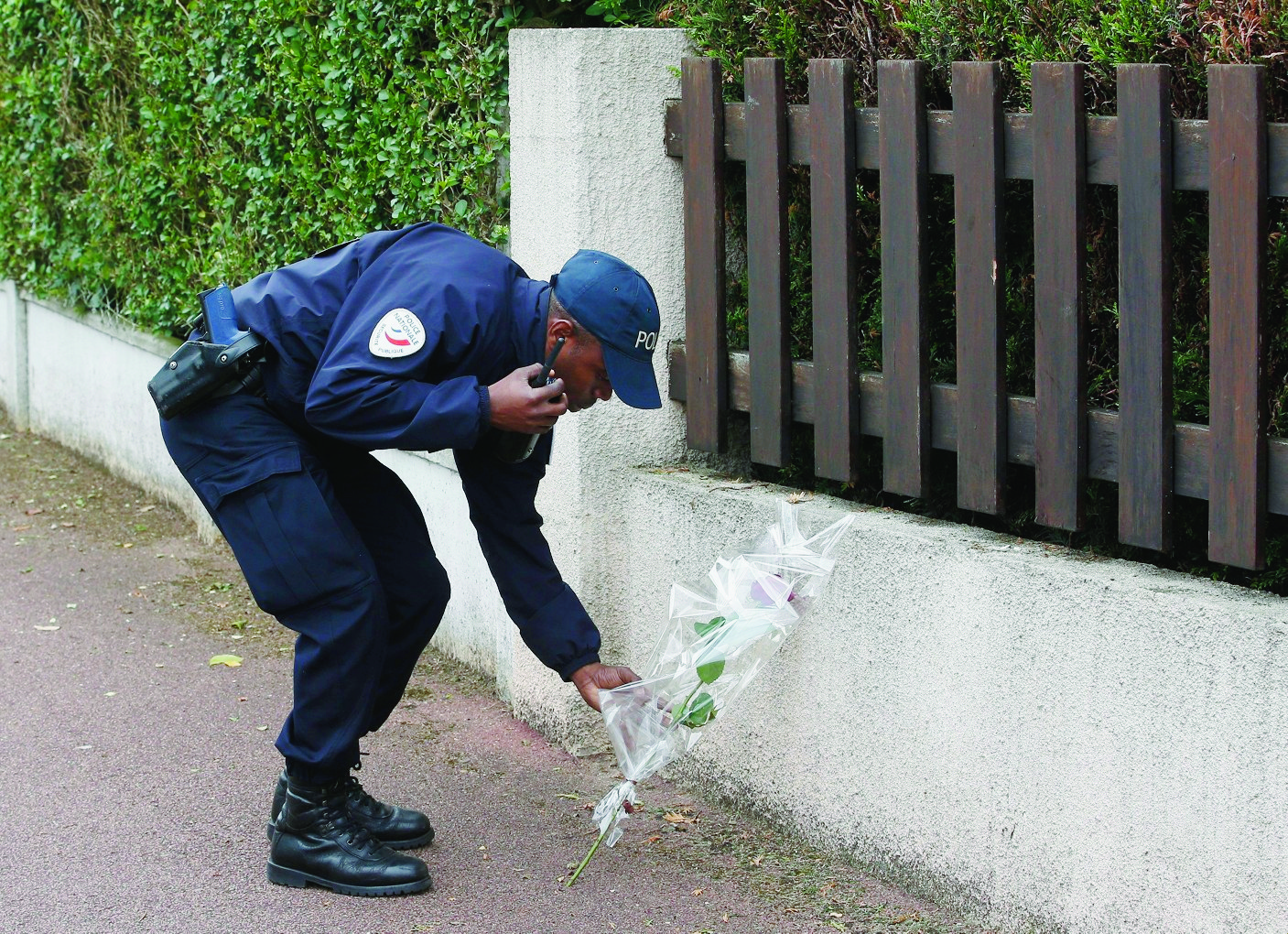 A French police officer lays flowers while paying tribute to his colleagues killed in a knife attack near their home in Magnanville, west of Paris, France, Tuesday, June 14, 2016. French President Francois Hollande says that the stabbing attack that left two police officials dead was "incontestably a terrorist act." (AP Photo/Thibault Camus) France Policeman Killed