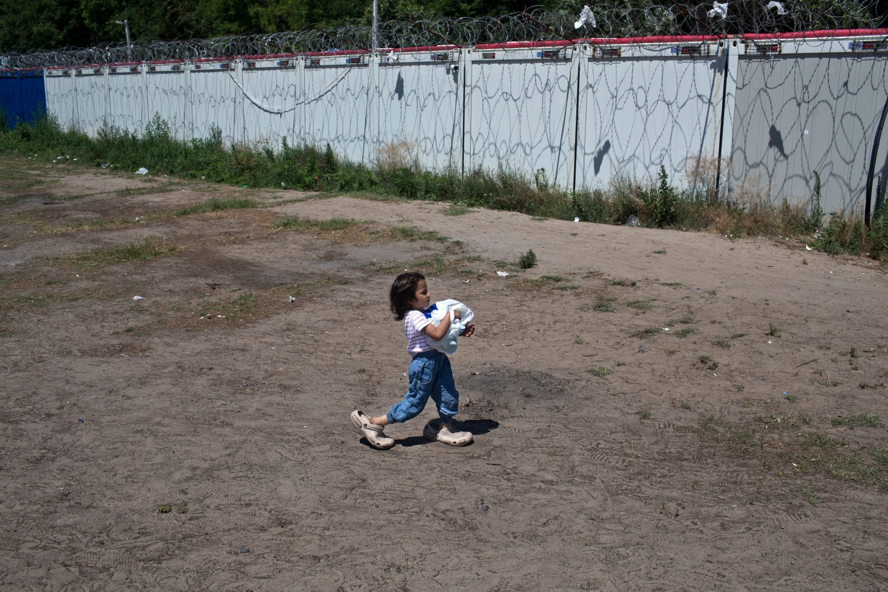A child carries an aid package at a makeshift camp for migrants and refugees situated meters away from the Serbian border with Hungary, in Horgos, Serbia, Monday, July 4, 2016. Waiting in the summer heat with limited running water, hundreds of refugees camping out on the Serbian-Hungarian border are facing uncertain prospects as EU nation Hungary prepares to implement new, tighter asylum rules on Tuesday. (AP Photo/Marko Drobnjakovic) Serbia Migrants Uncertain Future