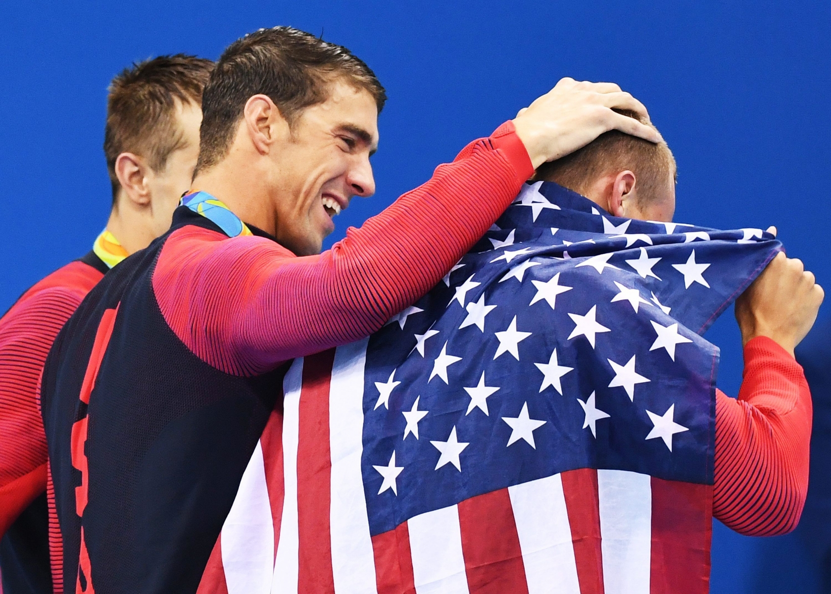 epa05463981 Geold medalists Michael Phelps of USA hugs his teammate Caeleb Dresser (R) next to Ryan Held (L) after the medal ceremony for the men's 4x100m Freestyle relay final race of the Rio 2016 Olympic Games Swimming events at Olympic Aquatics Stadium at the Olympic Park in Rio de Janeiro, Brazil, 07 August 2016.  EPA/BERND THISSEN