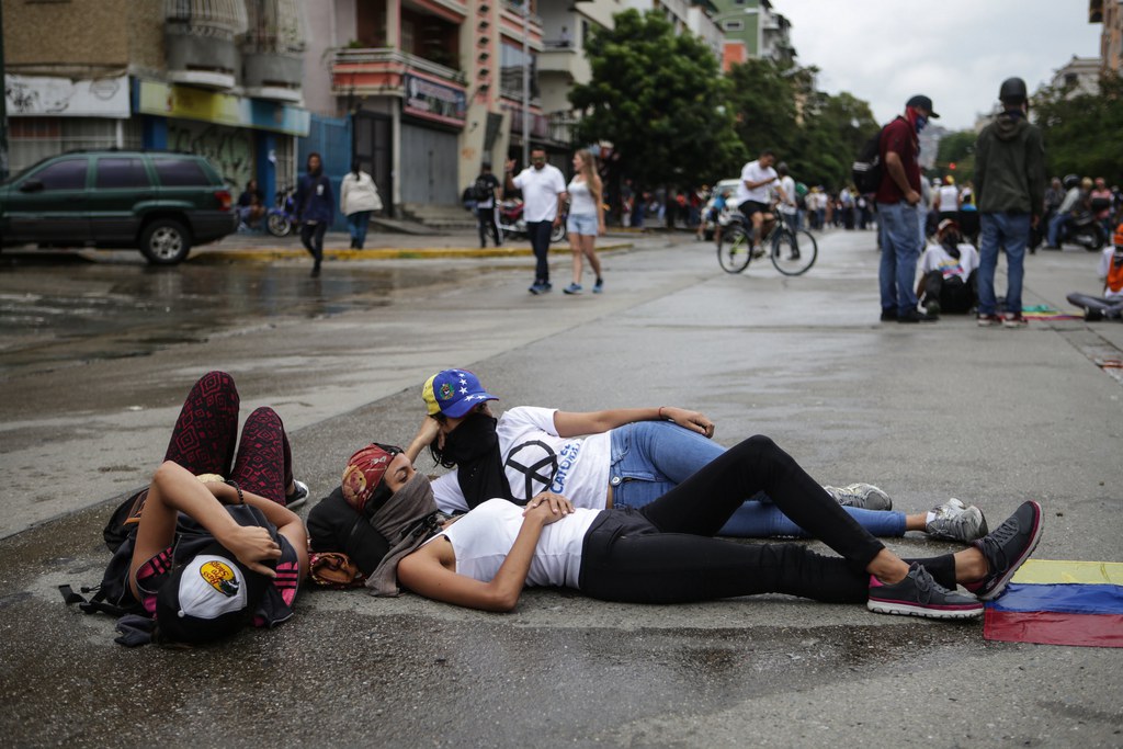 En début-d'après-midi à Caracas, parapluies et capes étaient de sortie sur la principale autoroute d'accès à la capitale, où les manifestants équipés de vivres et d'eau pour la journée, jouaient aux cartes, chantaient et lisaient, assis ou allongés sur le bitume.