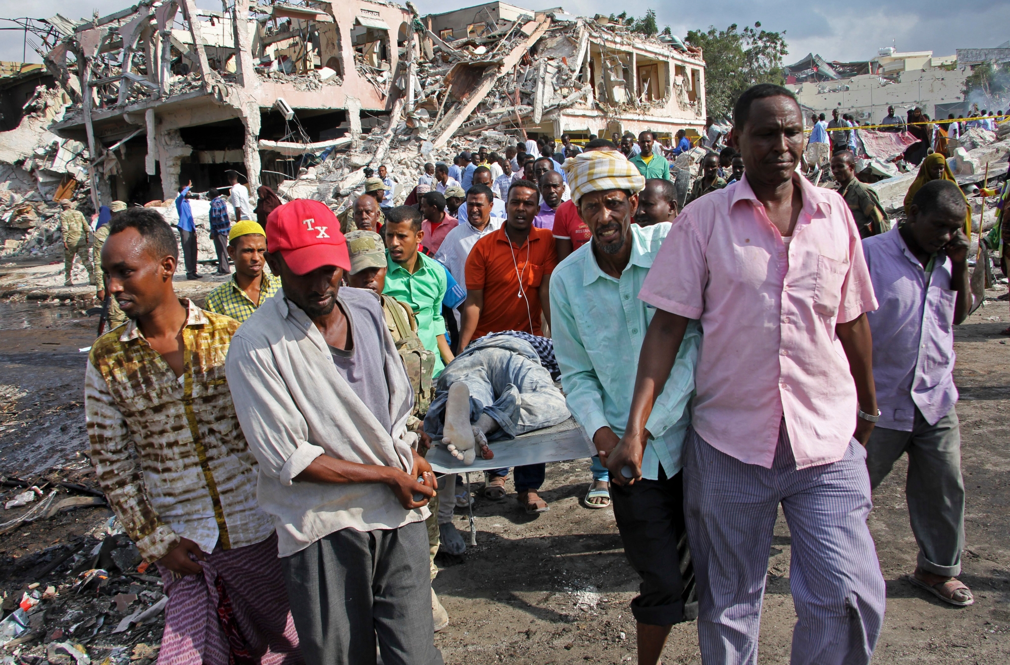 Somalis remove the body of a man killed in Saturday's blast, in Mogadishu, Somalia Sunday, Oct. 15, 2017. The death toll from the huge truck bomb blast in Somalia's capital rose to over 50 Sunday, with more than 60 others injured, as hospitals struggled to cope with the high number of casualties, security and medical sources said. (AP Photo/Farah Abdi Warsameh) Somalia Explosion