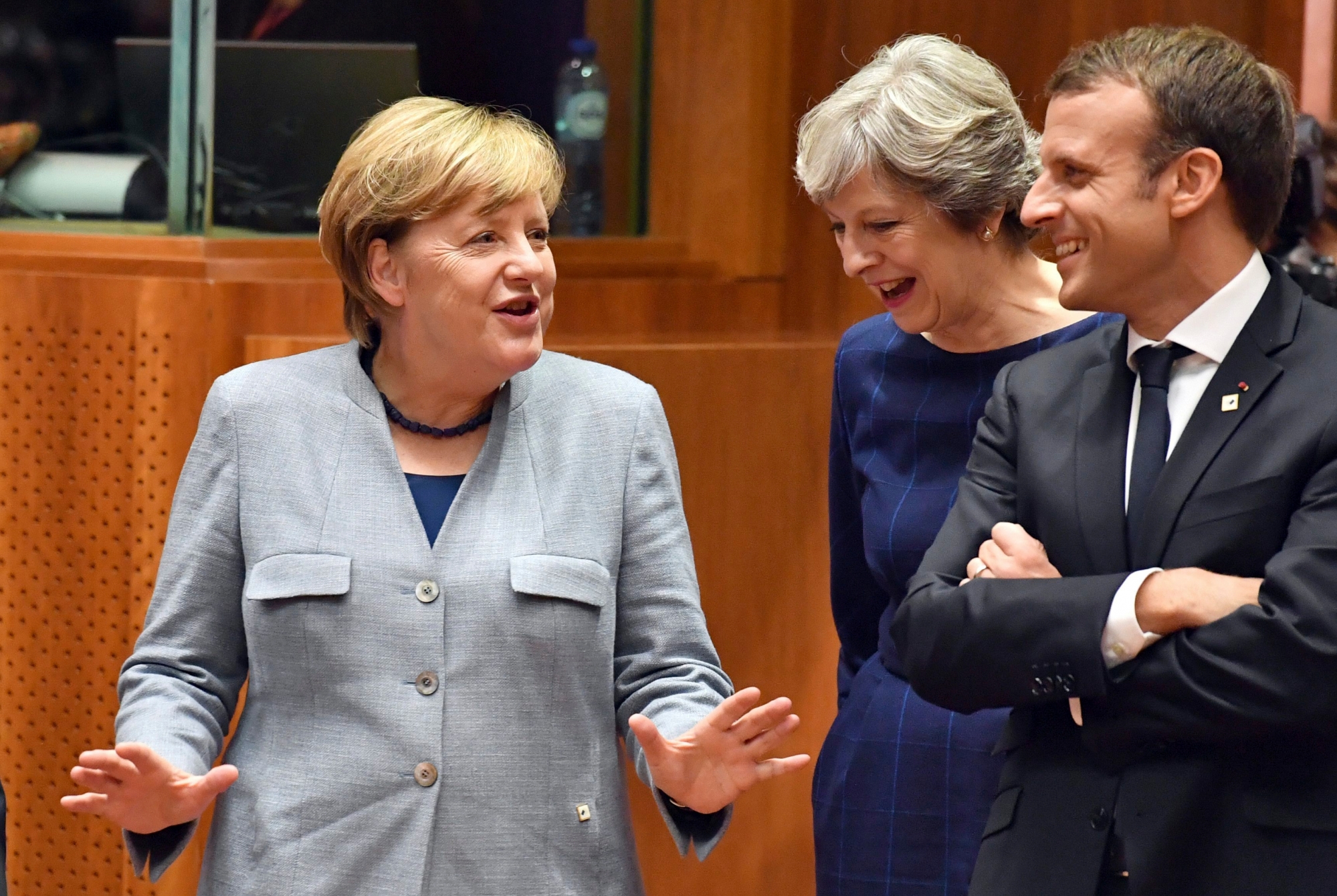 German Chancellor Angela Merkel, left, speaks with British Prime Minister Theresa May, center, and French President Emmanuel Macron prior to a round table meeting at an EU summit in Brussels on Thursday, Oct. 19, 2017. British Prime Minister Theresa May headed to a European Union summit Thursday with a pledge to treat EU residents well once Britain leaves the bloc. (AP Photo/Geert Vanden Wijngaert) Belgium EU Brexit