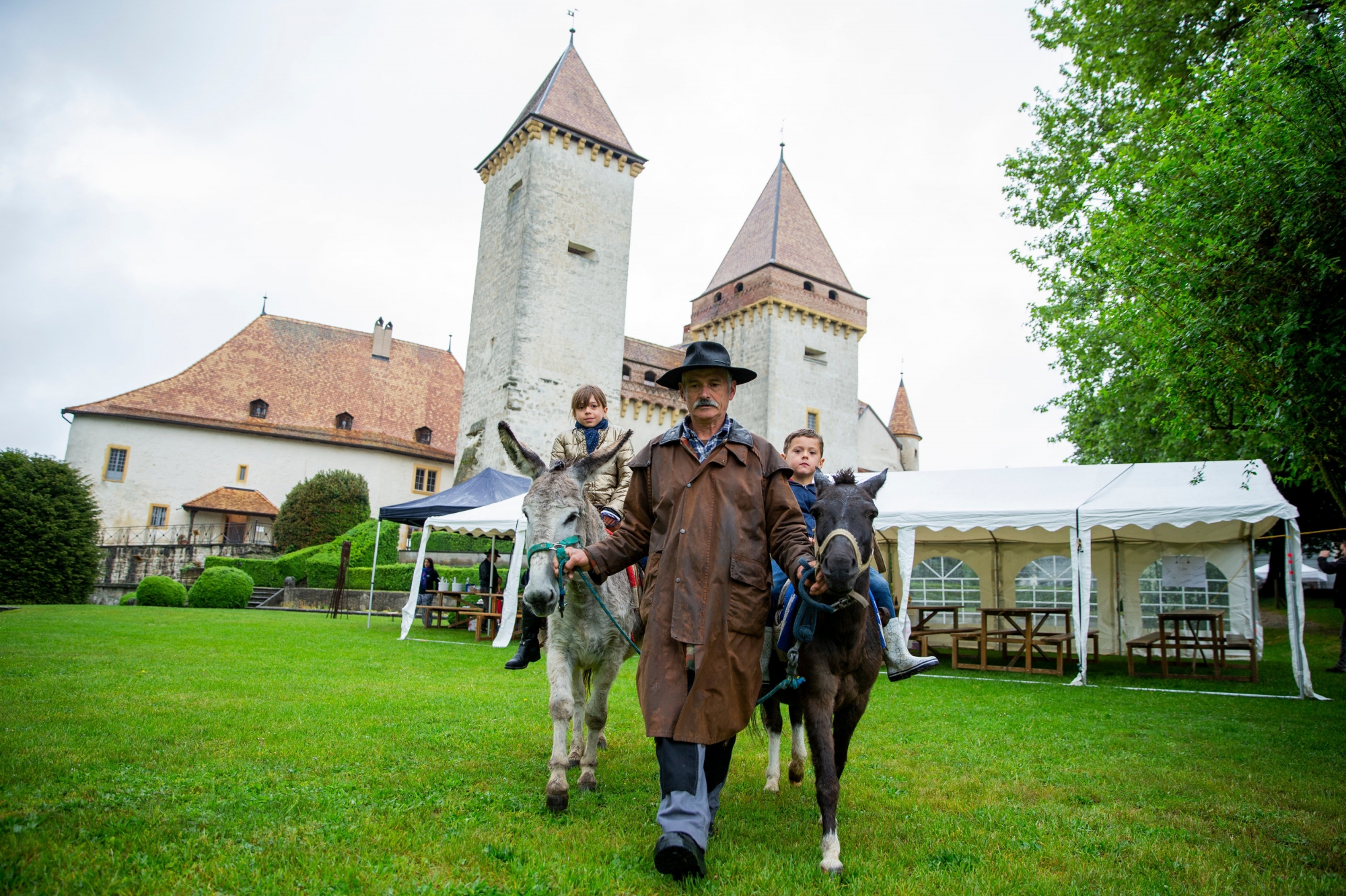 Victoire (9 ans) et Livio (4 ans et demi) posent fièrement sur les ânes de Jean-Michel Esnault, devant le château de La Sarraz.