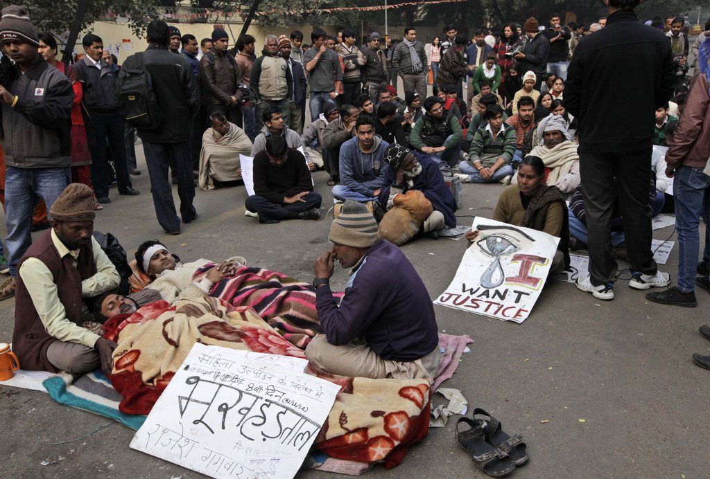 Indian men lie on a street while on a hunger strike during a protest in New Delhi, India, Monday, Dec. 31, 2012. A young woman who died after being gang-raped and beaten on a bus in India's capital was cremated privately as millions of grieving, angry residents demanded greater protection for women from sexual violence. A placard in front reads as, "Against women harassment, 8th day of Hunger Strike."  (AP Photo/Manish Swarup)
