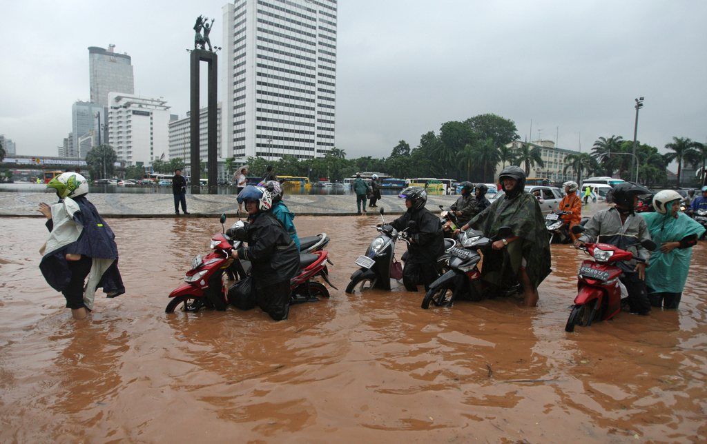 Indonesians push their motorcycles through a flooded street in Jakarta, Indonesia, Thursday, Jan. 17, 2013. Flooding caused by monsoon rains have forced thousands of people to flee their homes in Indonesia's capital. (AP Photo/Achmad Ibrahim)