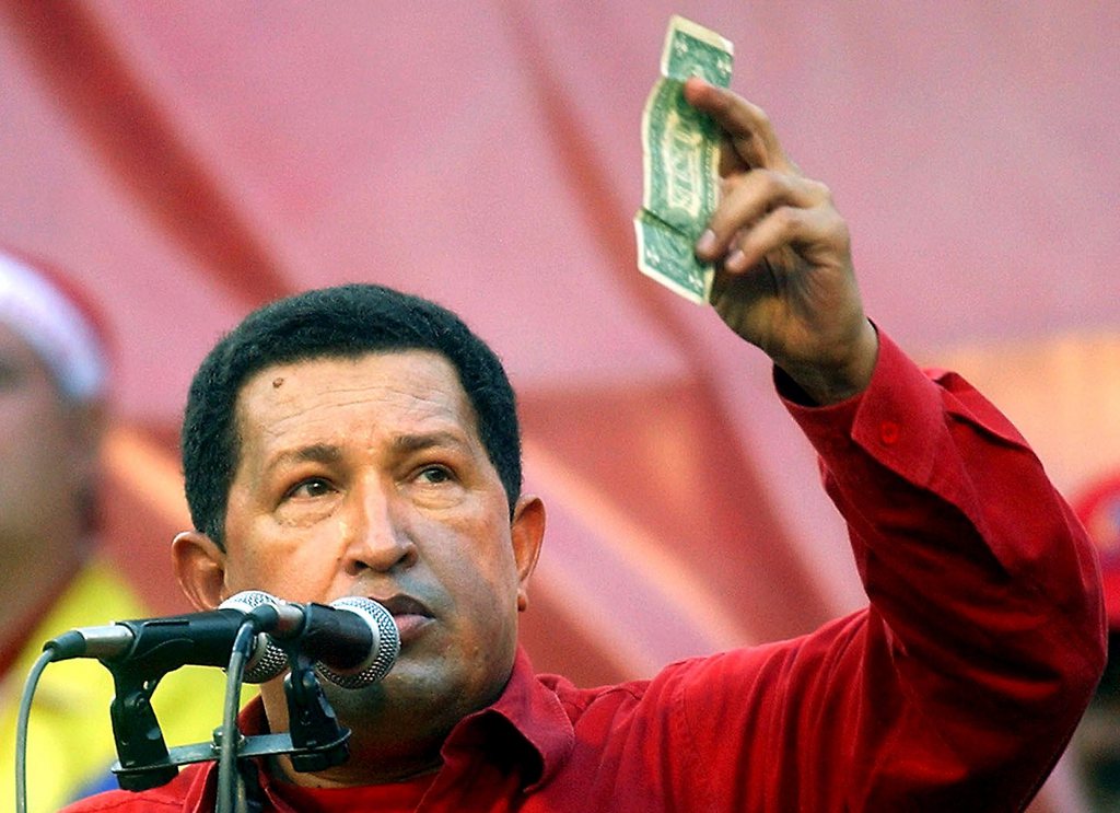 FILE - In this Jan. 23, 2005 photo, Venezuela's President Hugo Chavez holds up a U.S. dollar bill and challenges U.S. President George W. Bush to bet which of them will remain in power longer at a rally in Caracas, Venezuela. Venezuela's Vice President Nicolas Maduro announced that Chavez died on Tuesday, March 5, 2013, at age 58 after a nearly two-year bout with cancer. (AP Photo/Fernando Llano, File)