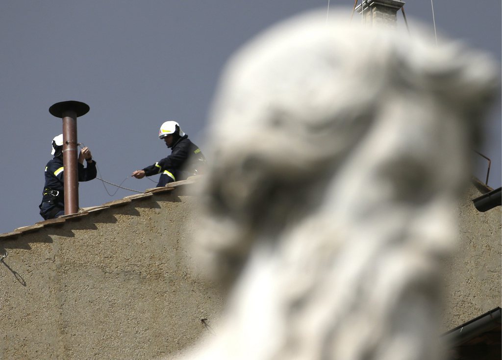 Firefighters place the chimney on the roof of the Sistine Chapel, where cardinals will gather to elect the new pope, at the Vatican, Saturday, March 9, 2013. The preliminaries over, Catholic cardinals are ready to get down to the real business of choosing a pope. And even without a front-runner, there are indications they will go into the conclave Tuesday with a good idea of their top picks. The conclave date was set Friday during a vote by the College of Cardinals, who have been meeting all week to discuss the church's problems and priorities, and the qualities the successor to Pope Benedict XVI must possess. (AP Photo/Gregorio Borgia)