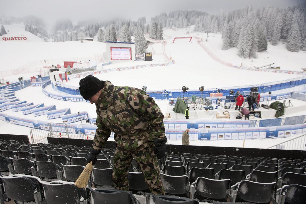 A Swiss army member removes snow from tribune before the men's World Cup Super G of the Alpine Ski World Cup finals, in Parpan-Lenzerheide, Switzerland, Thursday, March 14, 2013. The two Super G races, men and women are postponed because of the fog and snowfall. (KEYSTONE/Alexandra Wey)