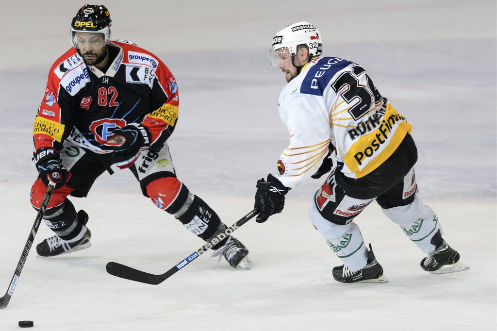 Le défenseur fribourgeois Michael Ngoy (gauche) a perdu l'avantage de la glace jeudi soir face à l'attaquant bernois Ivo Ruethemann lors de l'acte 1 de la finale des play-offs de LNA de hockey.